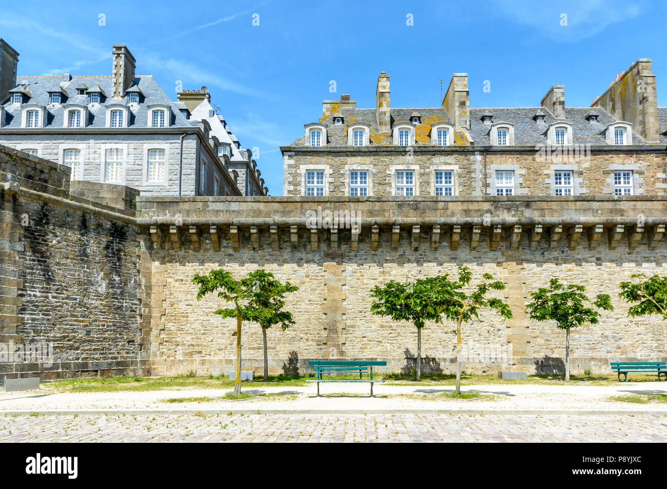 The surrounding wall of the old city of Saint-Malo, France, with a park at the foot of the wall and residential buildings protruding above the rampart Stock Photo