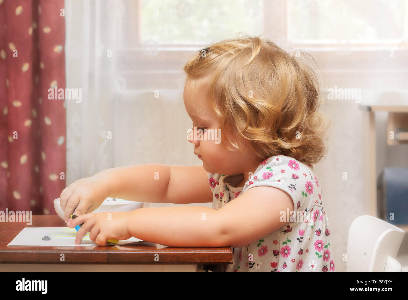 Soft portrait of two years blond kid, girl painting on the paper. Family life. Stock Photo