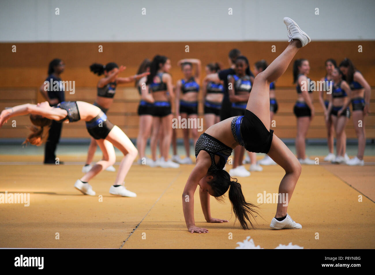 Young teenager cheerleaders dancing, acrobacy, acrobatic moves cheerleaders in blue in the air Stock Photo