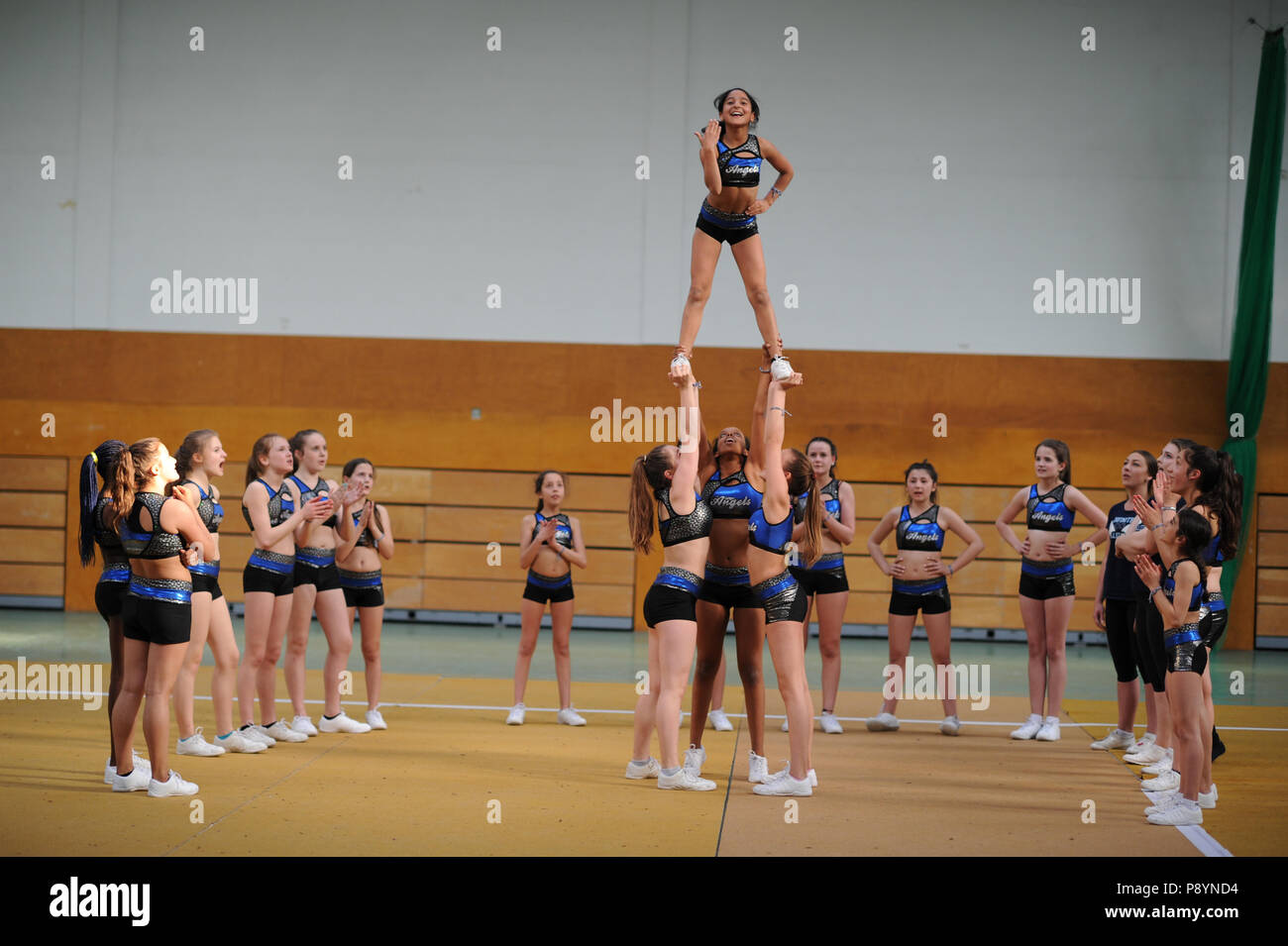 Young teenager cheerleaders dancing, acrobacy, acrobatic moves cheerleaders in blue in the air Stock Photo