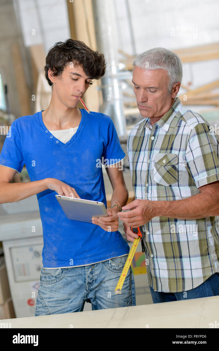 Young worker showing tablet to senior worker Stock Photo