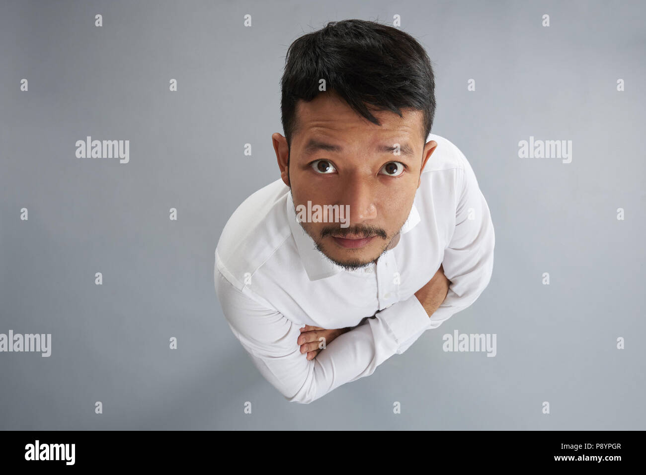 One asian man with crossed arms isolated on gray background above top view Stock Photo
