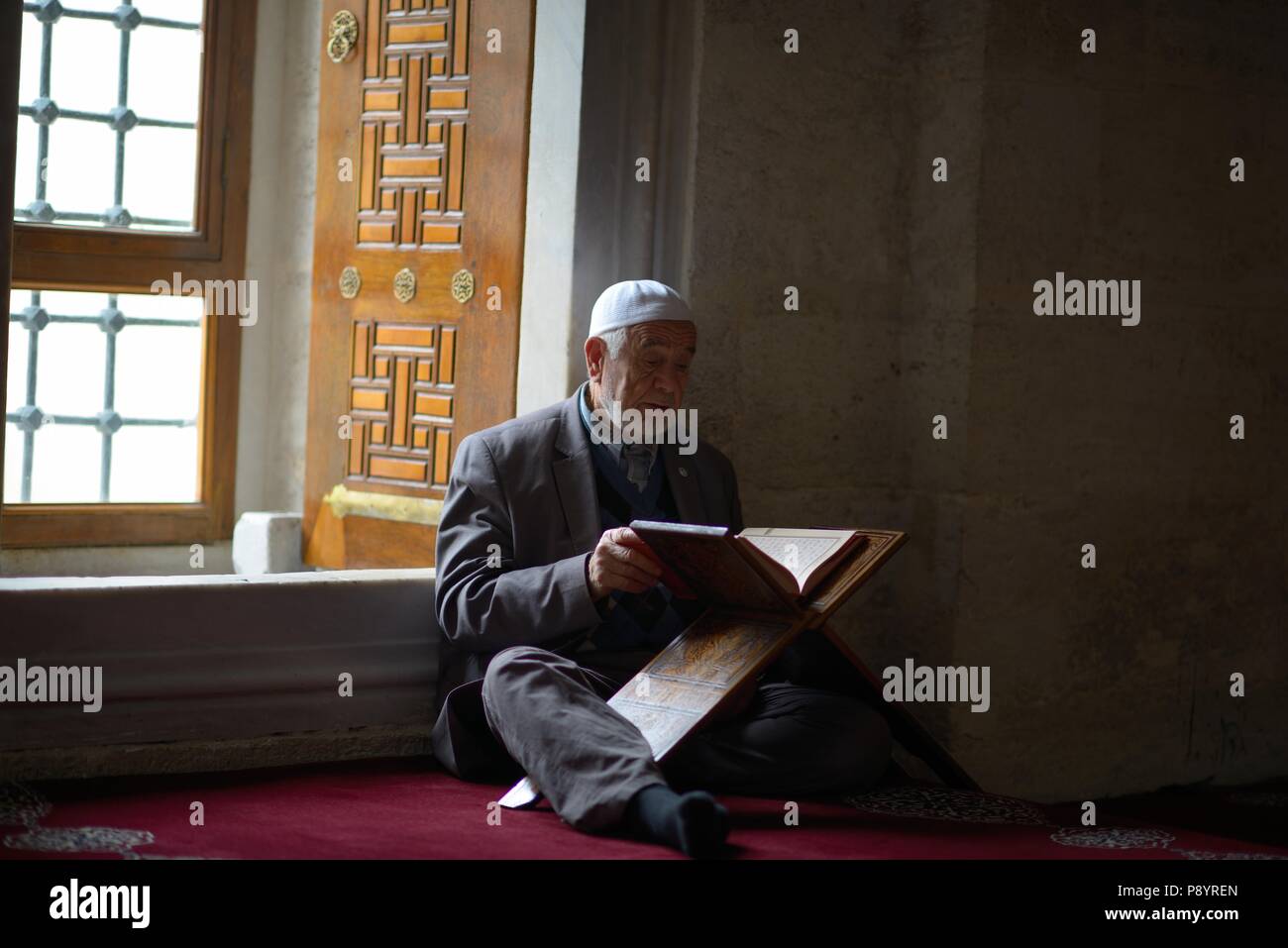 Old man reading Quran in the mosque Turkey Stock Photo