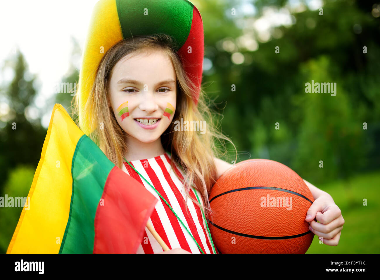 Funny little girl supporting and cheering her national basketball team during basketball championship. Cute Lithuanian team fan. Stock Photo