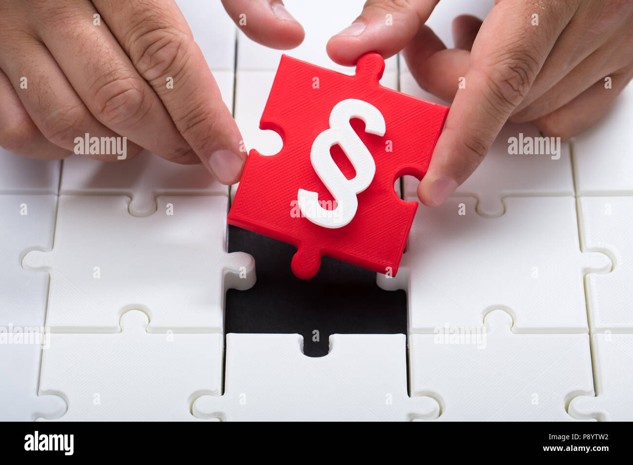 A person connecting last red piece with paragraph symbol into jigsaw puzzles Stock Photo
