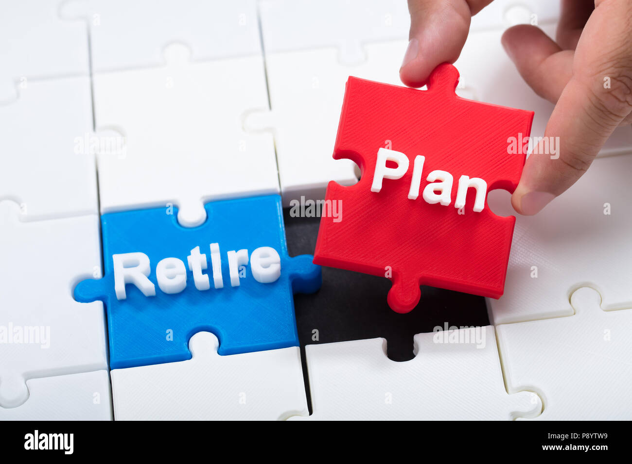 Close-up of a man's hand connecting retirement plan piece into jigsaw puzzle Stock Photo