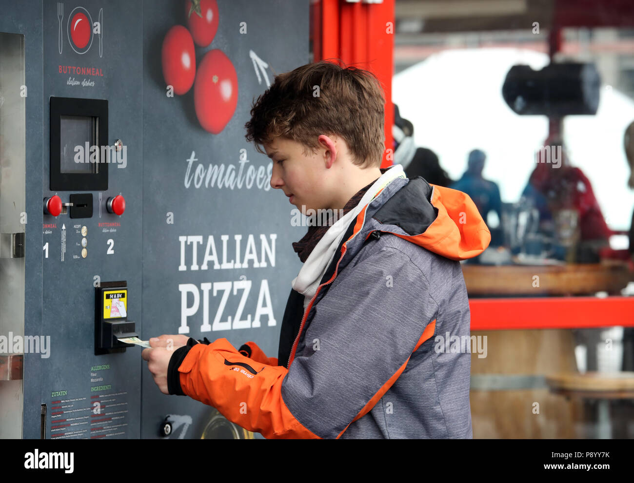 Reischach, Italy, boy is serving a pizza machine Stock Photo