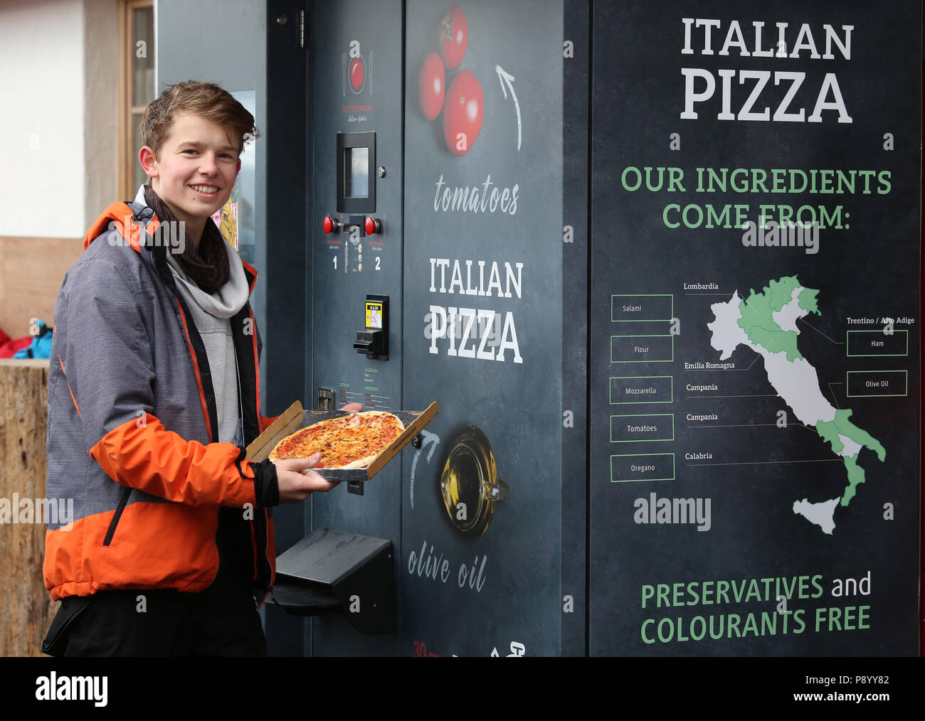 Reischach, Italy, boy proudly shows his pizza pulled out of a machine Stock Photo