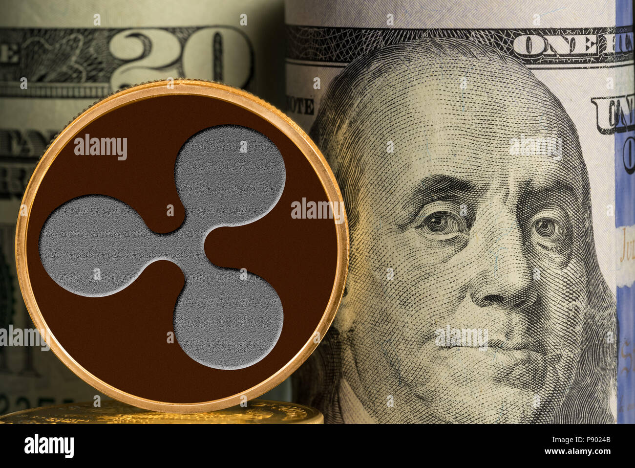 Single Ripple coin in front of bank rolls of US currency Stock Photo
