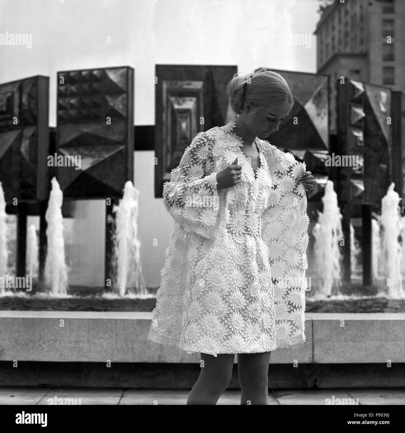 Berlin, GDR, young woman wearing the latest summer fashion in front of the fountain on Strausberger Platz Stock Photo