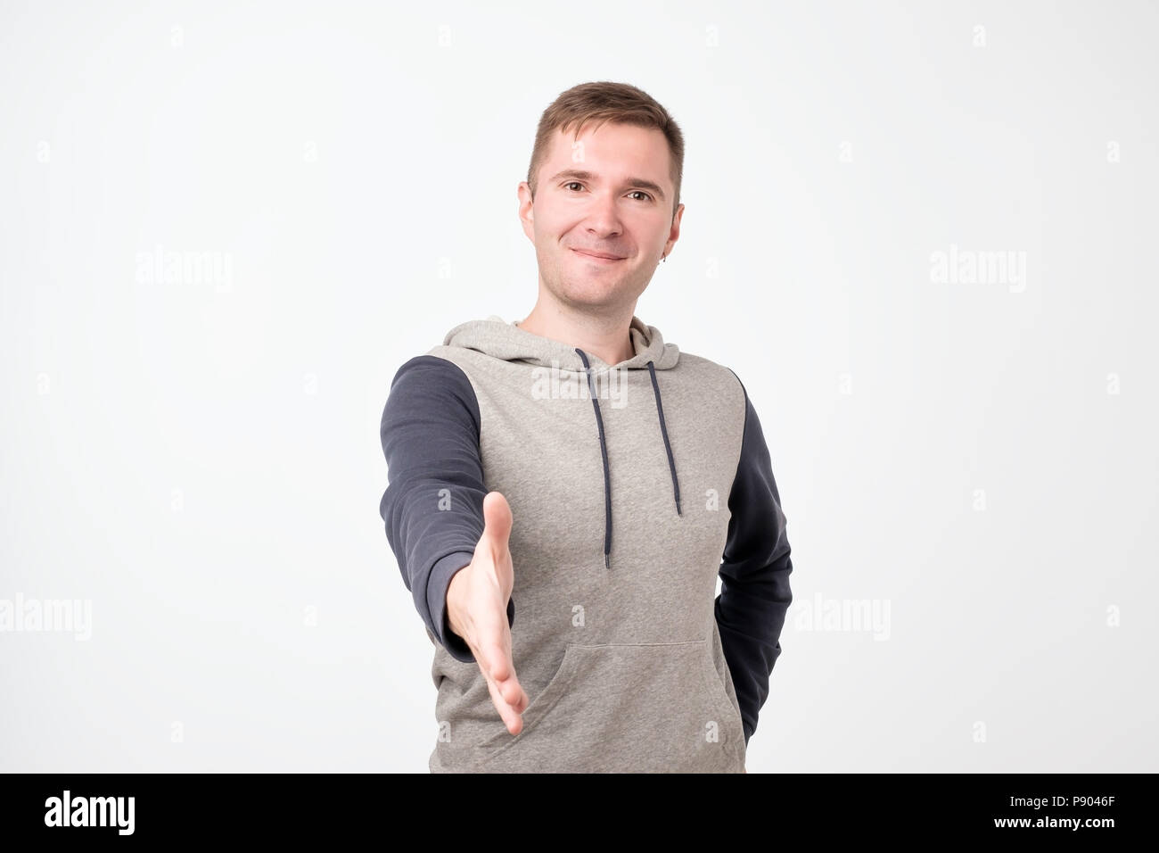 Handsome young man stretching out hand for shaking. Stock Photo