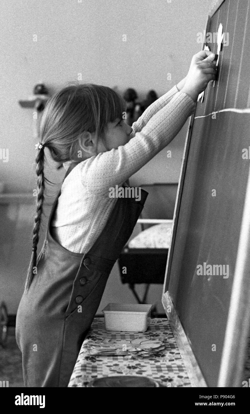 Berlin, GDR, girl stuck in the preschool figures of paper on a blackboard Stock Photo