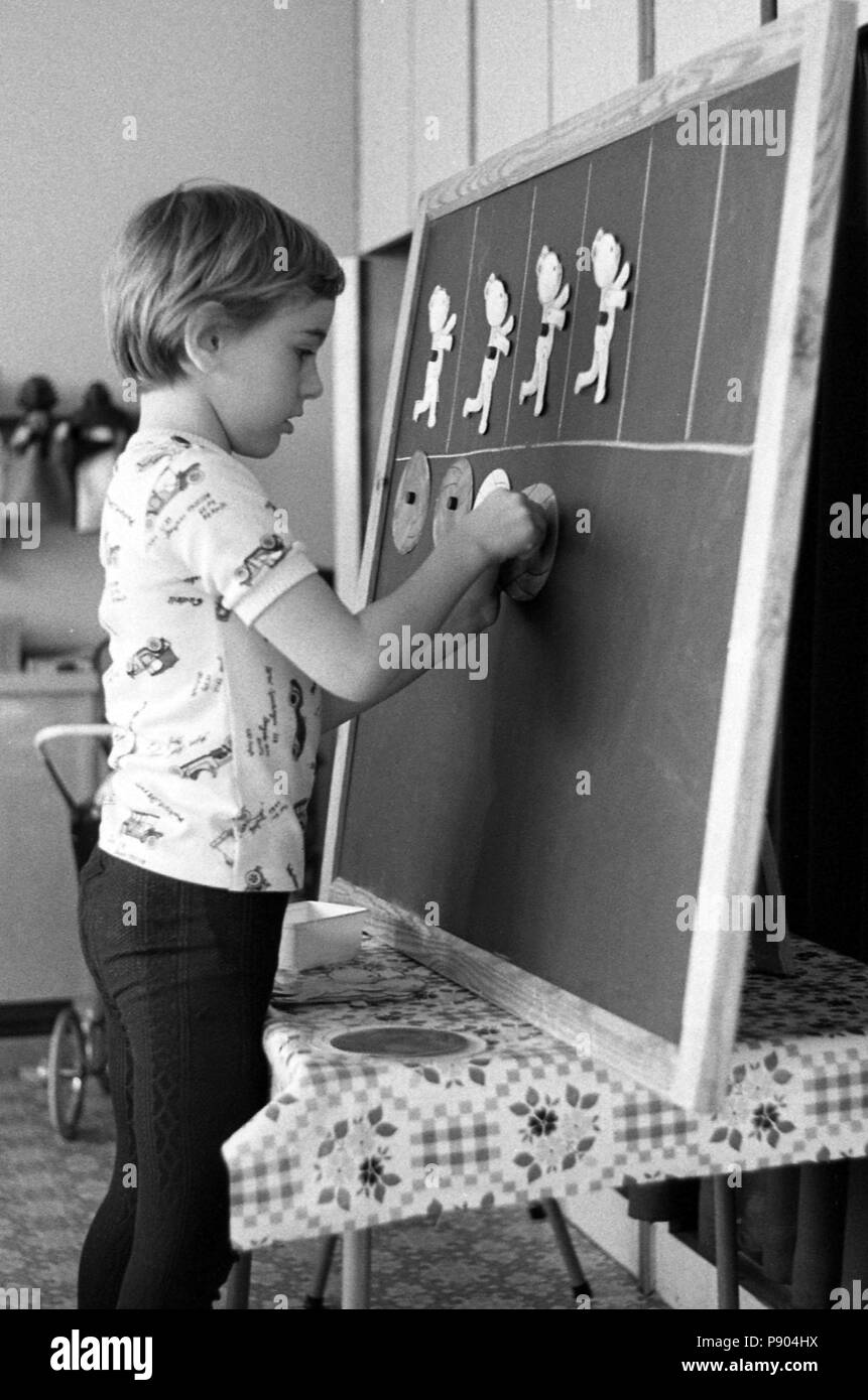 Berlin, East Germany, boy glues paper figures on a blackboard in preschool Stock Photo