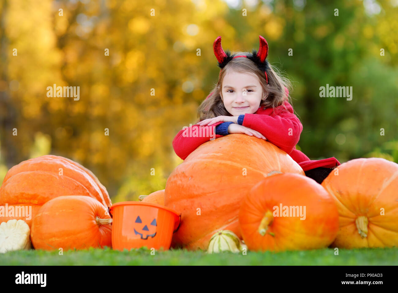 Adorable little girl wearing halloween costume having fun on a pumpkin