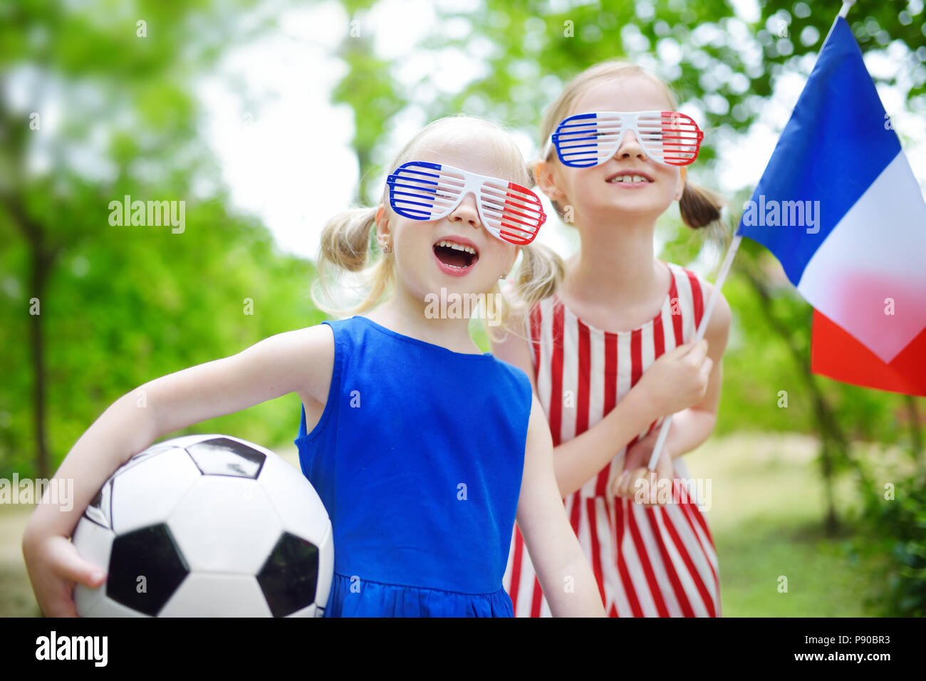 Two adorable little soccer fans cheering on summer day Stock Photo