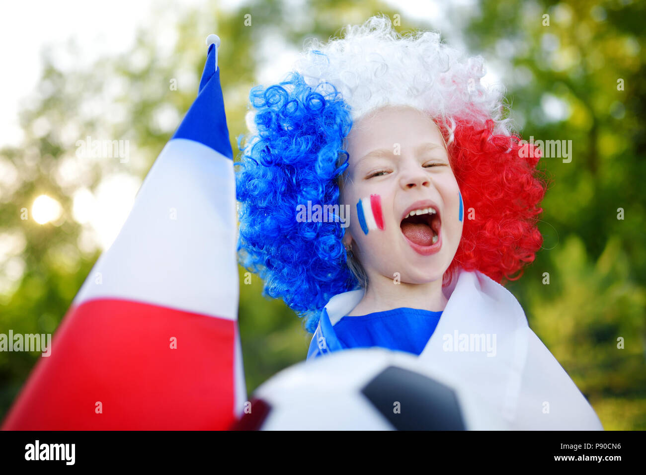 Funny little girl supporting and cheering her national football team during soccer championship Stock Photo