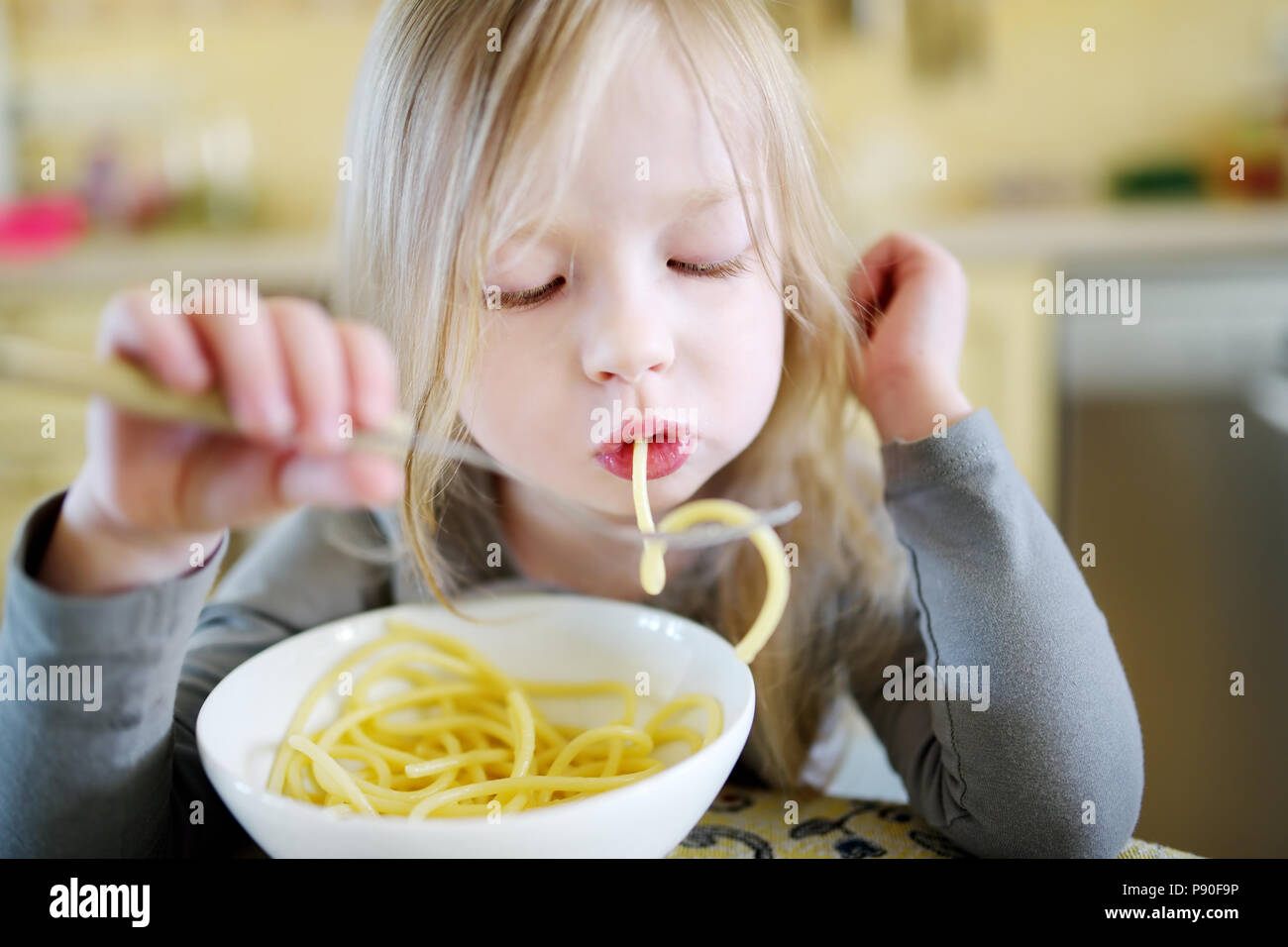 Cute funny little girl eating spaghetti at home Stock Photo - Alamy