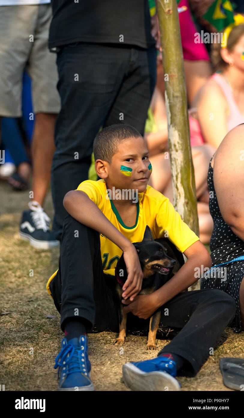 Brazil - June 27, 2018: Young Brazilian holds his dog as he watches his team play against Serbia at a free World Cup live telecast in Rio de Janeiro Stock Photo
