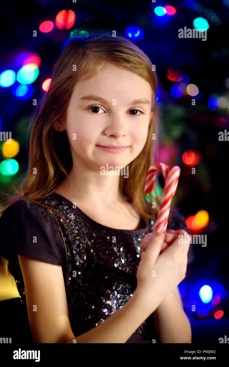 Christmas portrait of happy little girl by a fireplace in a cozy dark living room on Xmas eve Stock Photo