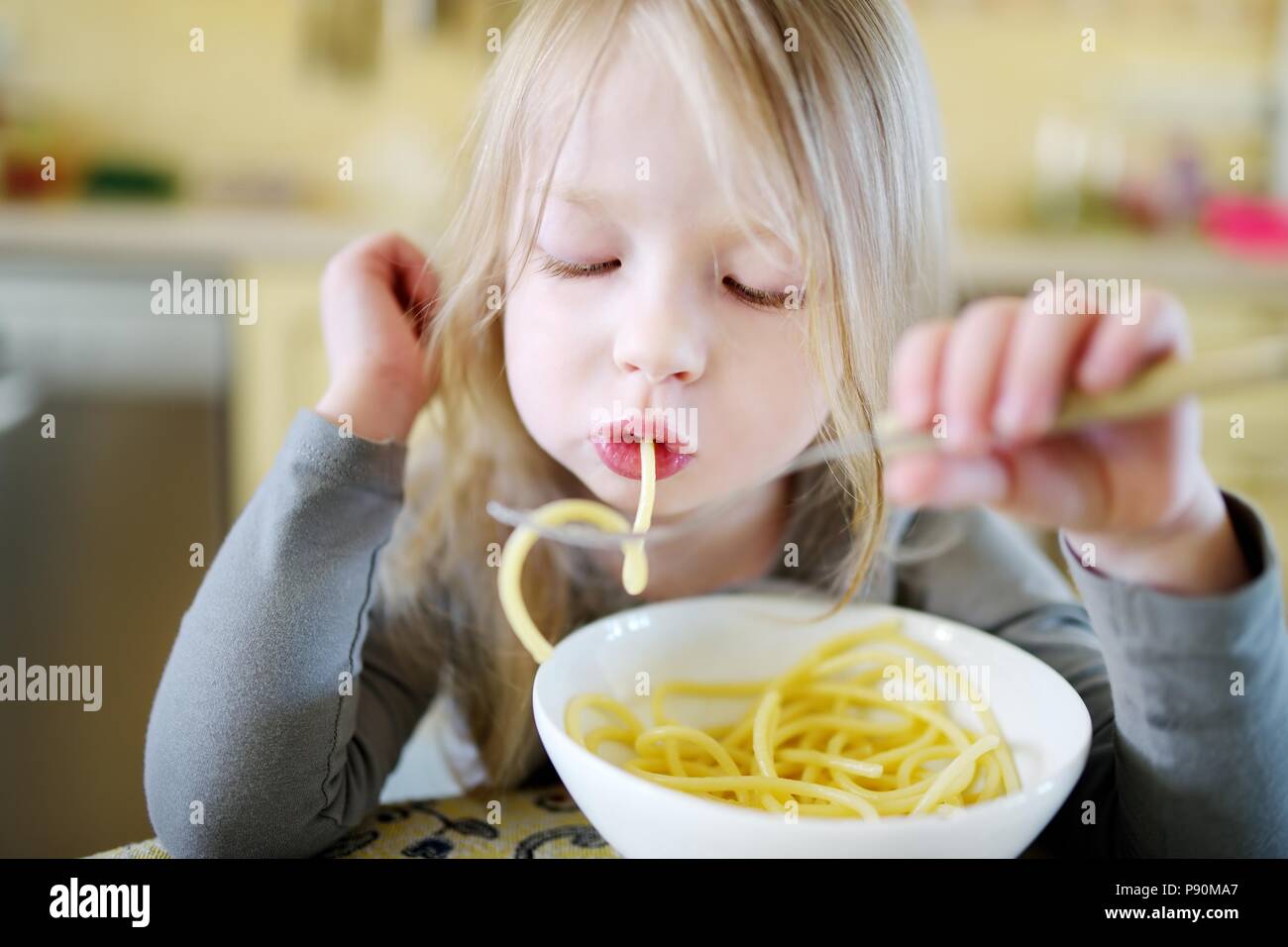 Cute funny little girl eating spaghetti at home Stock Photo - Alamy