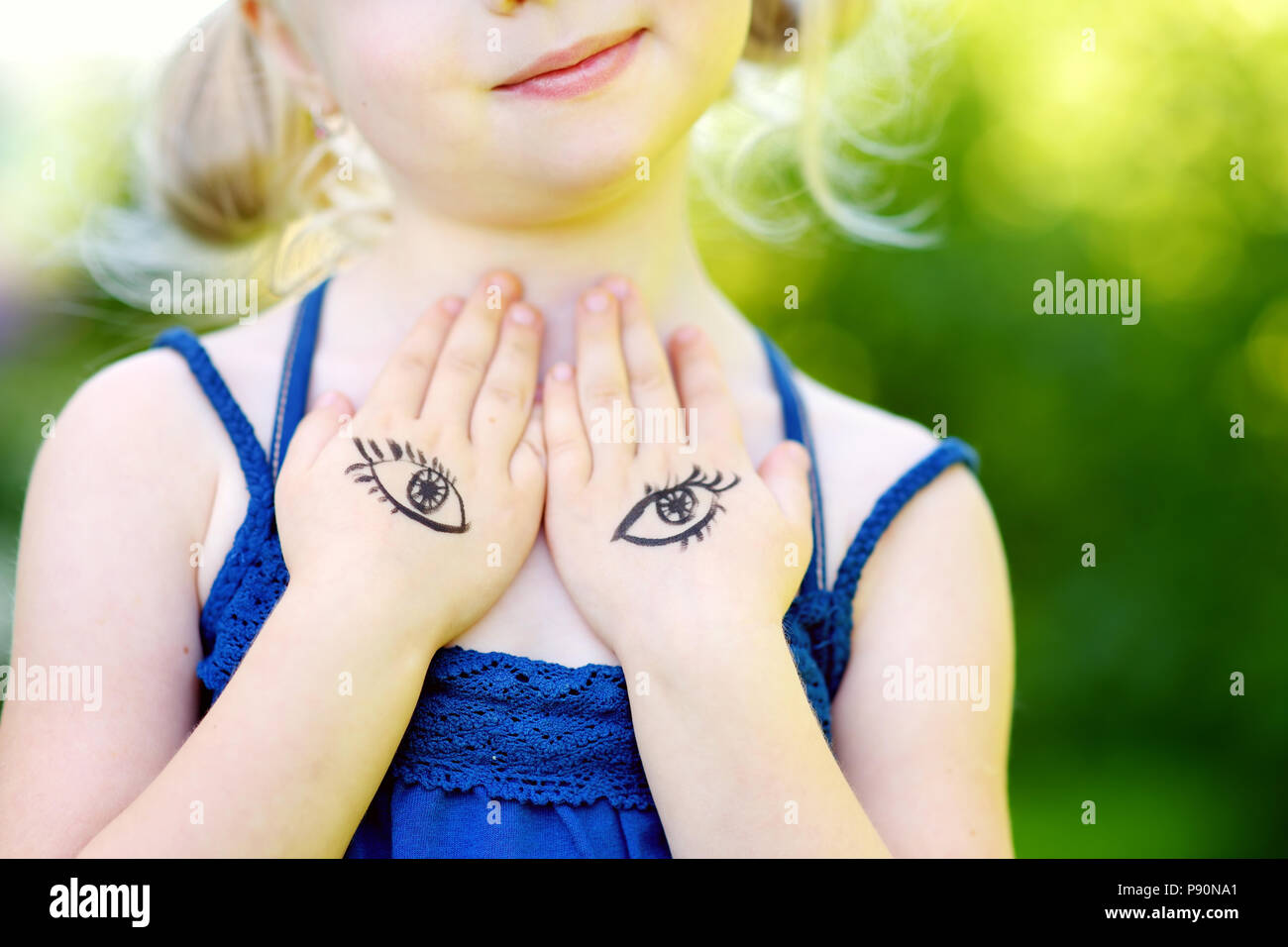 Cute little girl covering her chest with her hands on summer day ...