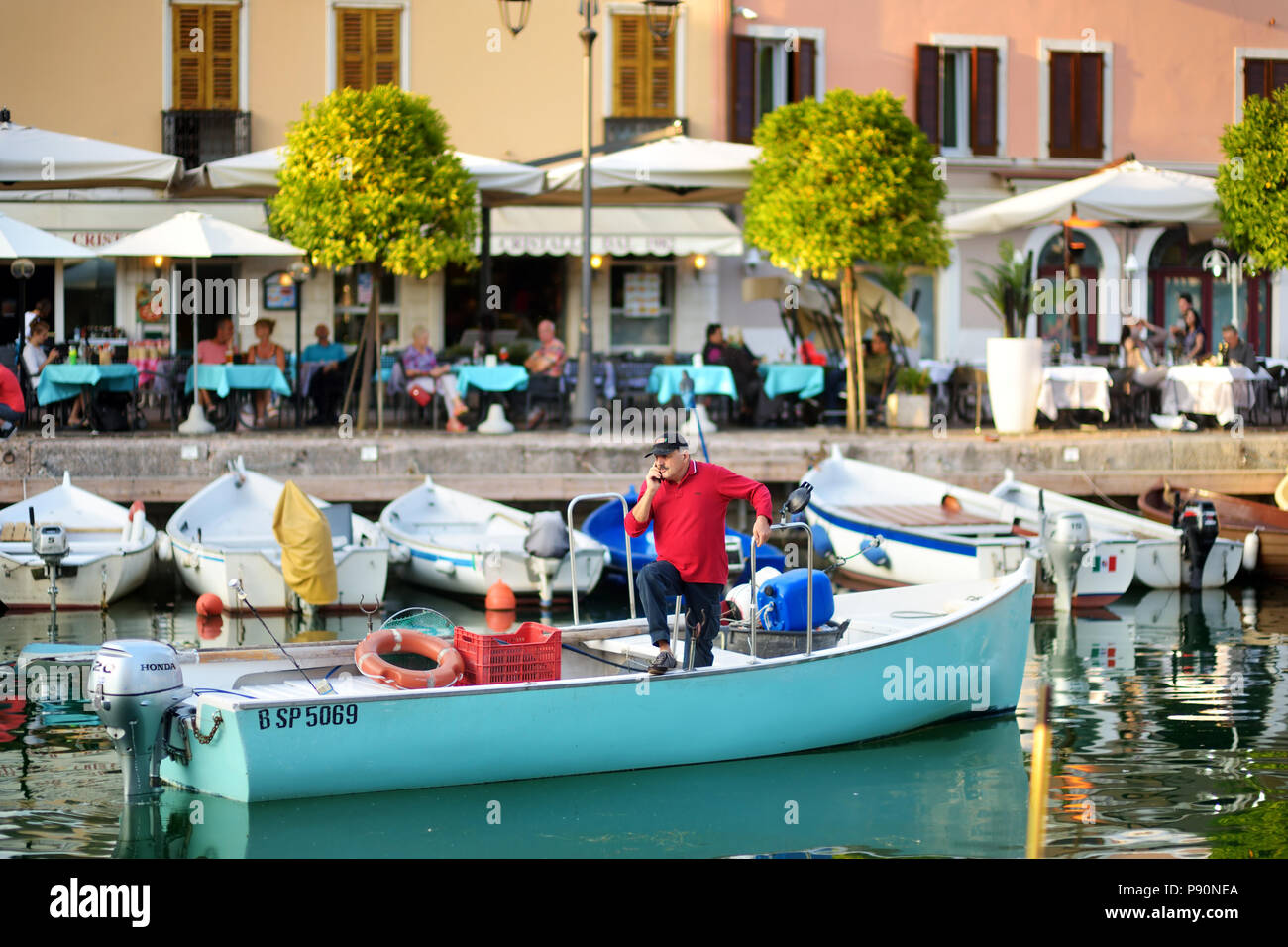 DESENZANO DEL GARDA, ITALY - SEPTEMBER 23, 2016: Fisherman in a boat in Desenzano del Garda, a town and comune in the province of Brescia, in Lombardy Stock Photo