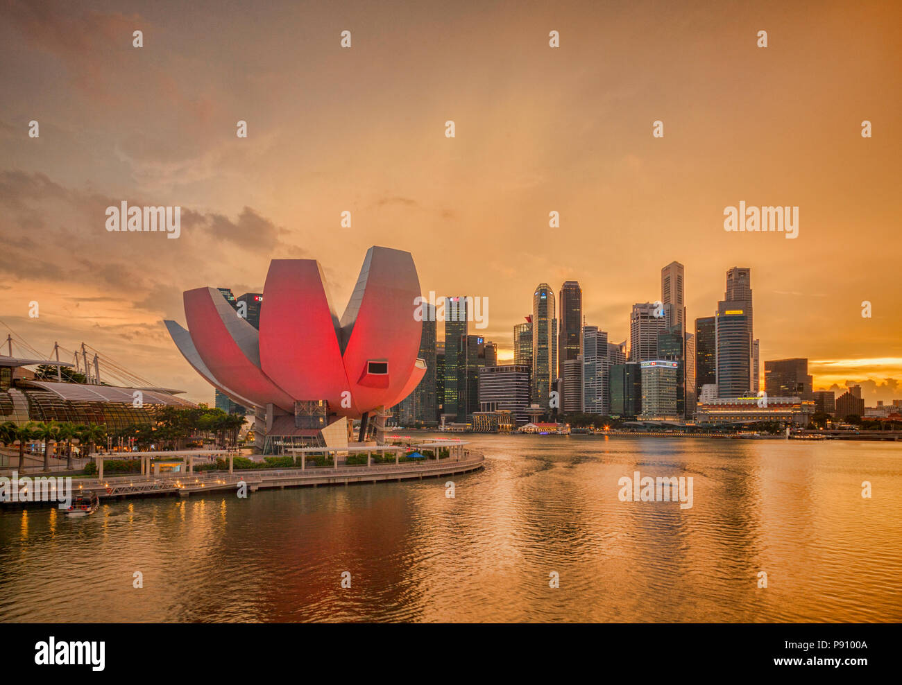 Singapore skyline  under an orange sky as a thunderstorm begins, with the Art and Science Museum illuminated in pink. Architect was Moshe Safdie. Stock Photo