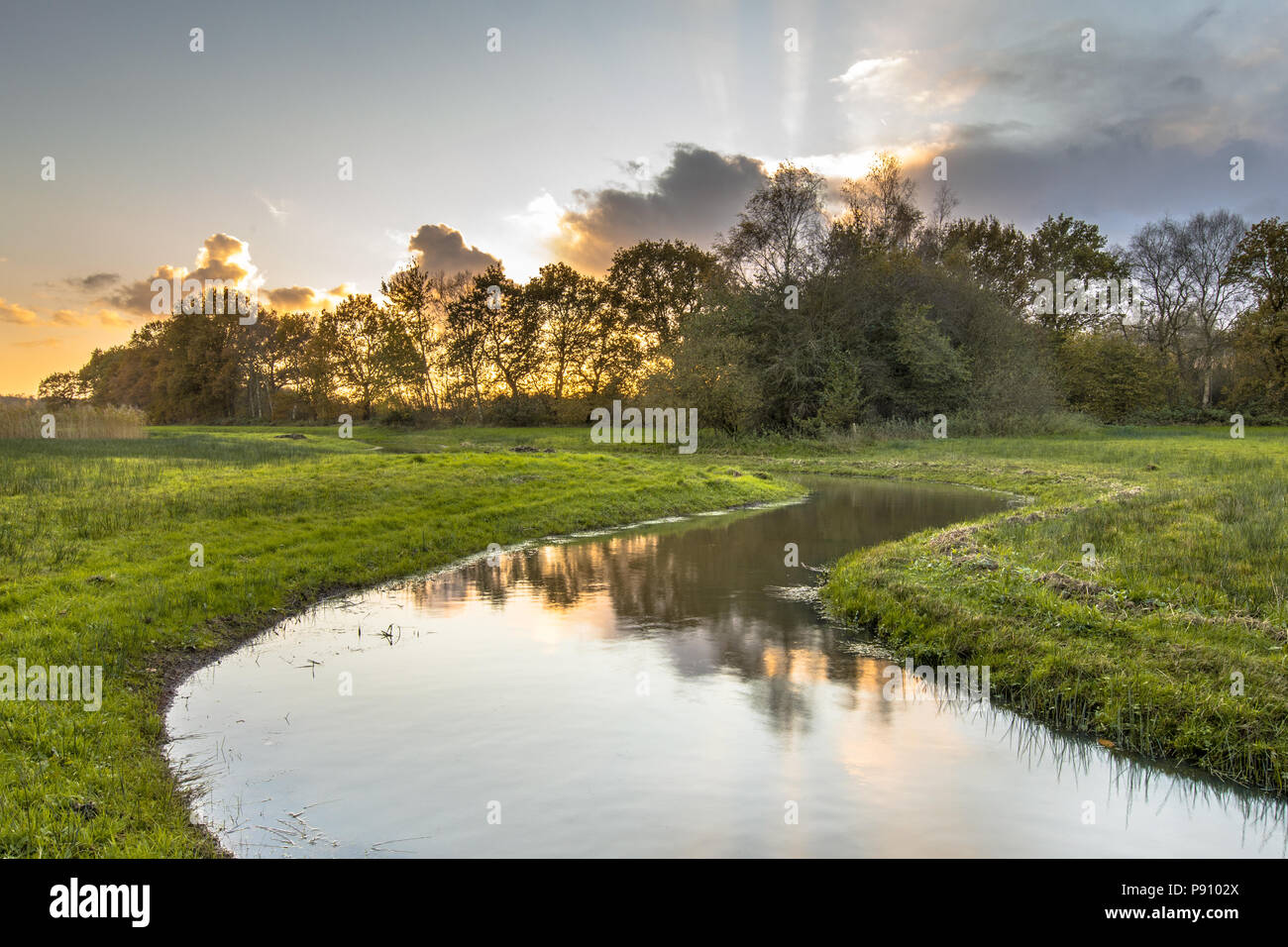 Sunset over meandering creek in small river valley in Drenthe, Netherlands Stock Photo