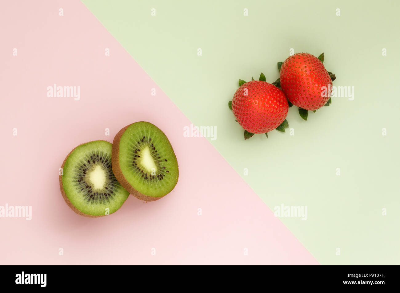 Two Kiwi half's and two Strawberries on duo colored background Stock Photo