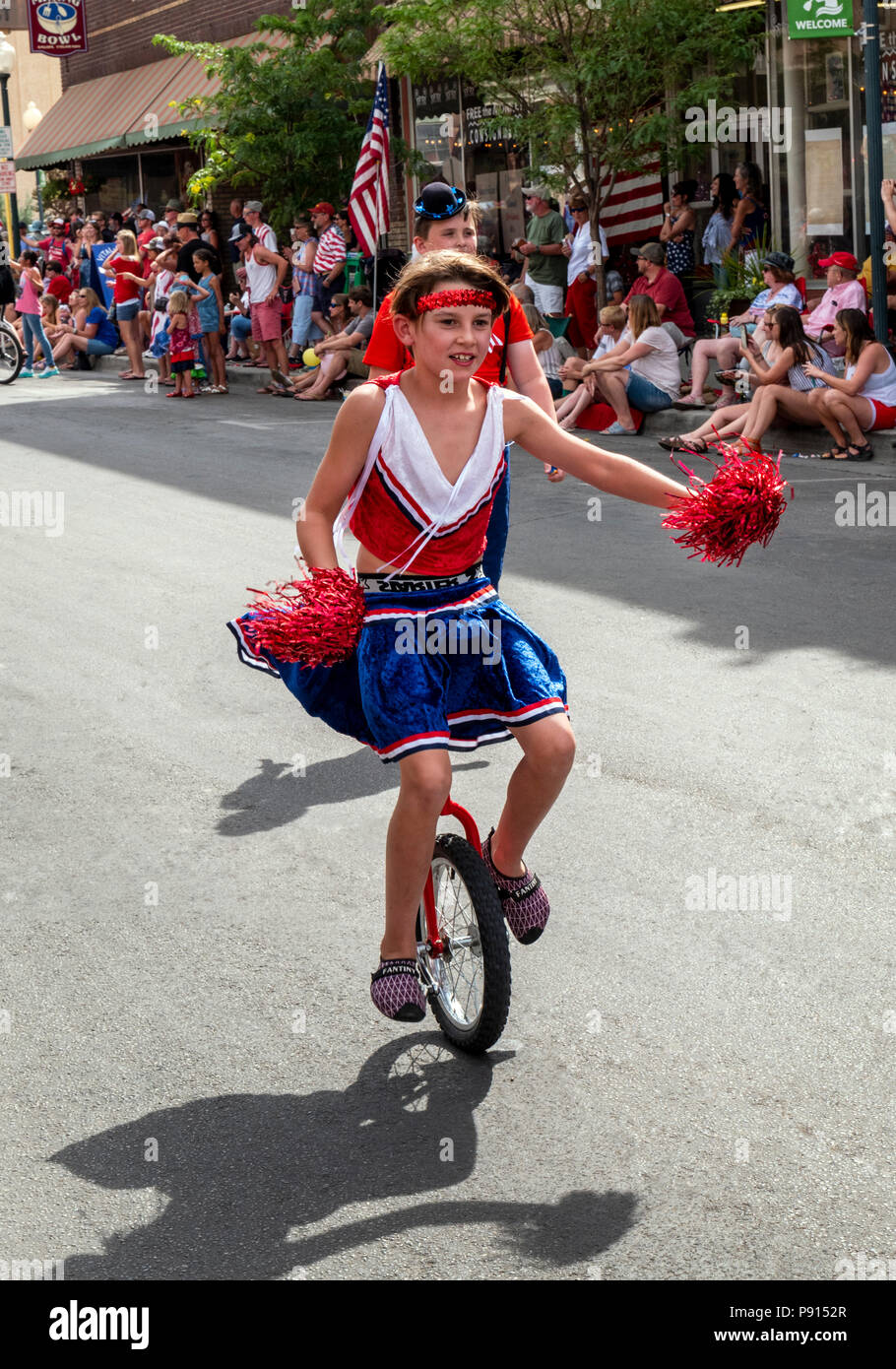 Salida Circus child riding unicycle in march in annual Fourth of July Parade in the small mountain town of Salida; Colorado; USA Stock Photo