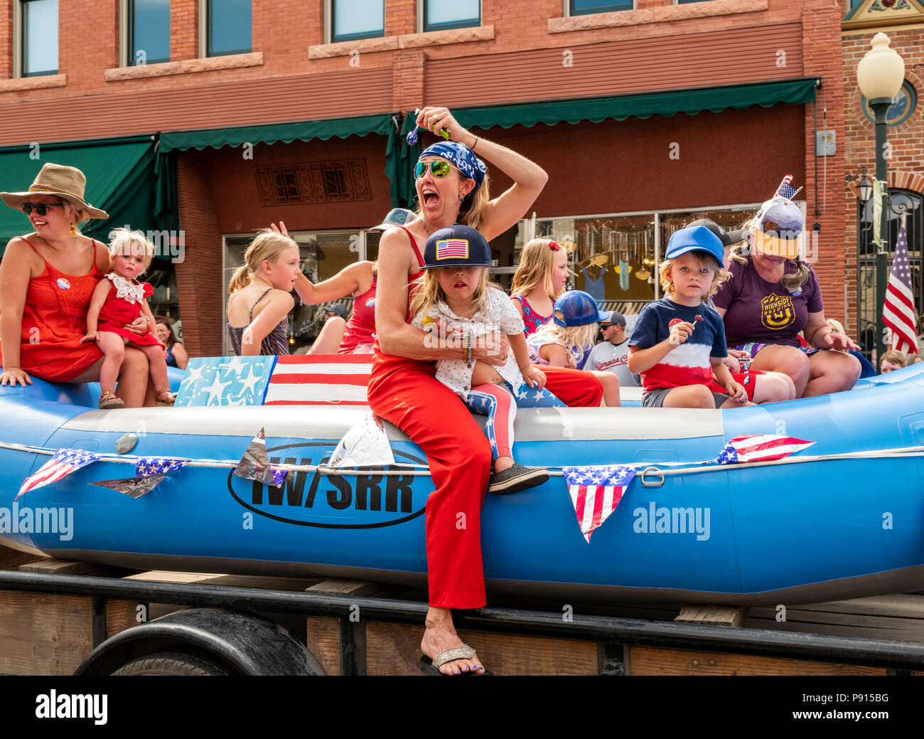 Families with children ride in boat float; annual Fourth of July Parade