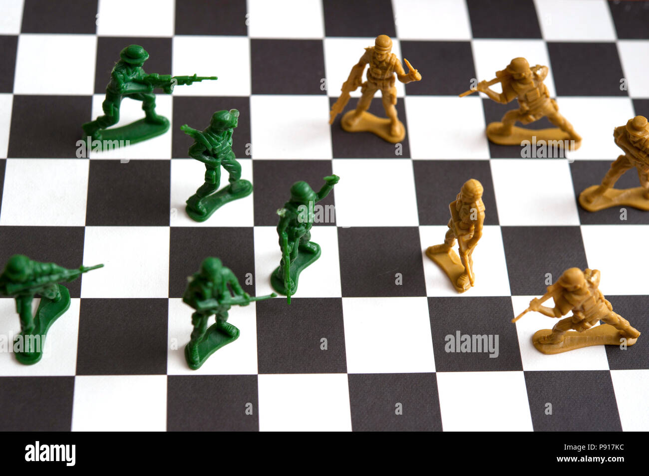 two armies of plastic toy soldiers facing each other on a checkerboard Stock Photo