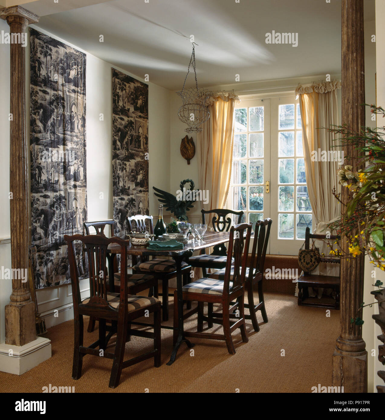 Heavy wood chairs at table in dining room with Toile-de-Jouy wall hangings  and sisal carpet Stock Photo - Alamy