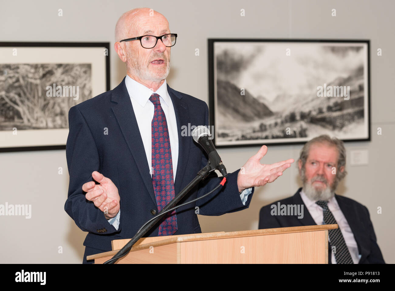 Oriel Môn, Llangefni, Gwynedd, Wales, UK. Friday 13 July 2018. The Opening night and prize awards for the centenary and fourth Kyffin Williams Drawing Prize exhibition, sponsored by ITV Cymru Wales and Rogers Jones auctioneers, was held at Oriel Môn, with David Rogers Jones (L) speaking about the student prize that his company of auctioneers sponsored, whilst David Meredith (R) looks on. Credit: Michael Gibson/Alamy Live News Stock Photo