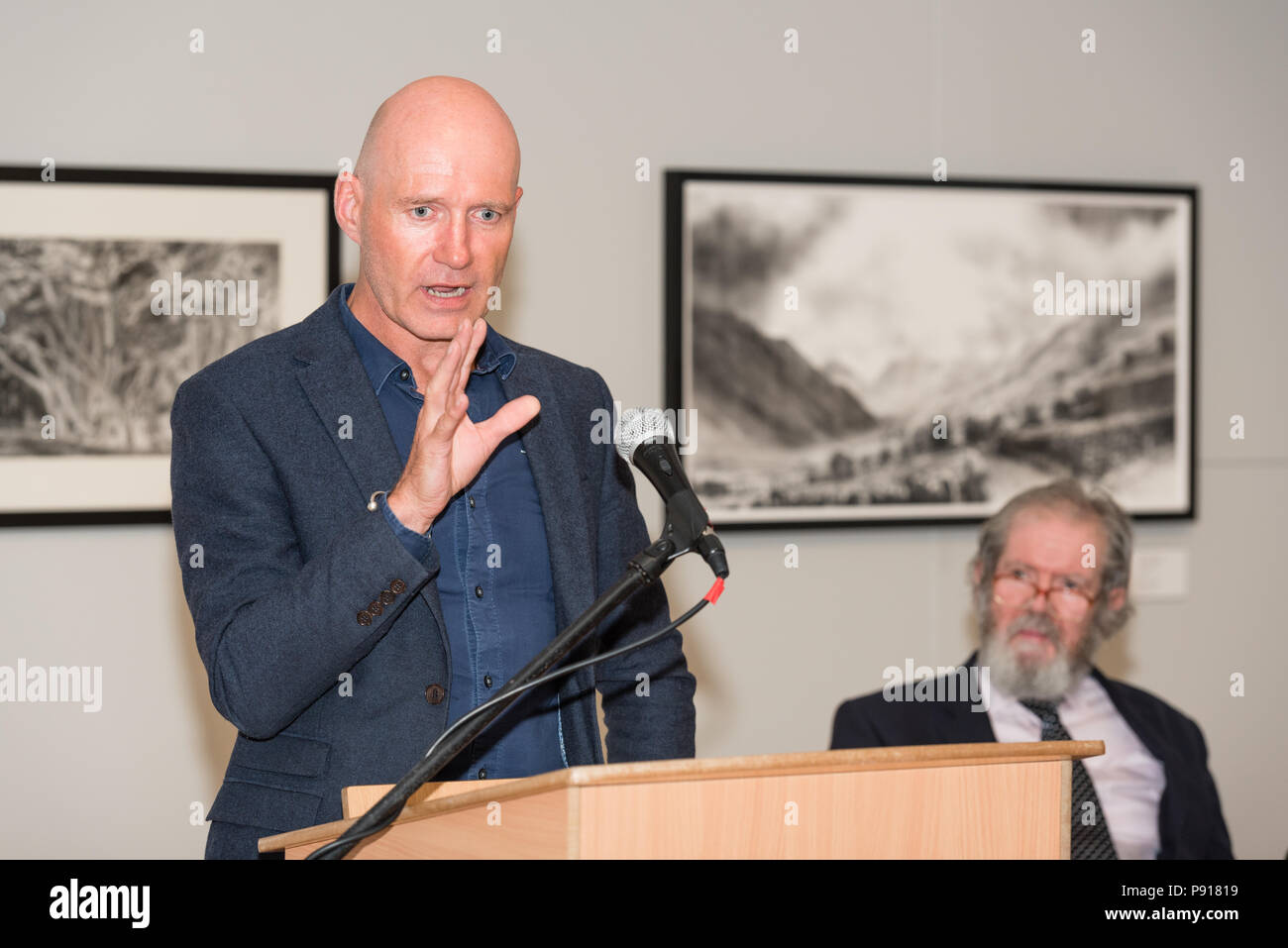 Oriel Môn, Llangefni, Gwynedd, Wales, UK. Friday 13 July 2018. The Opening night and prize awards for the centenary and fourth Kyffin Williams Drawing Prize exhibition, sponsored by ITV Cymru Wales and Rogers Jones auctioneers, was held at Oriel Môn, with Phil Henfrey Head of News ITV Cymru (L) speaking about his memories of Kyffin Williams, whilst David Meredith (R) listens intently. Credit: Michael Gibson/Alamy Live News Stock Photo