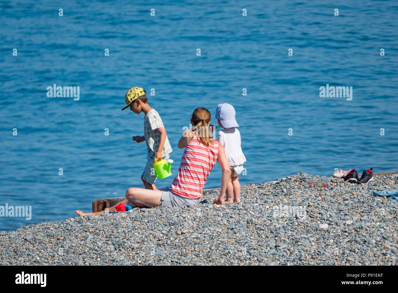 Aberystwyth Wales UK, Saturday 14 July 2018  UK Weather: People head to the beach and the sea on a bright and very warm sunny Saturday morning in Aberystwyth on the west coast of Wales. The long period of hot  and unusually dry weather is continuing, with temperatures  again  climbing to over 30ºc in parts of the UK this weekend  photo credit: Keith Morris / Alamy Live News Stock Photo