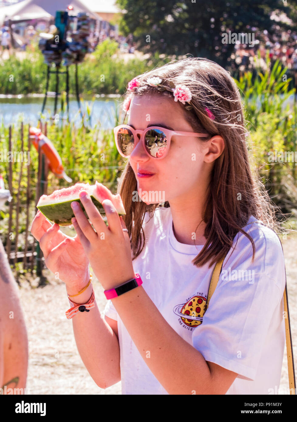 Young festival goer eating watermelon at Latitude Festival, Henham Park, Suffolk, England, 14th July, 2018 Stock Photo