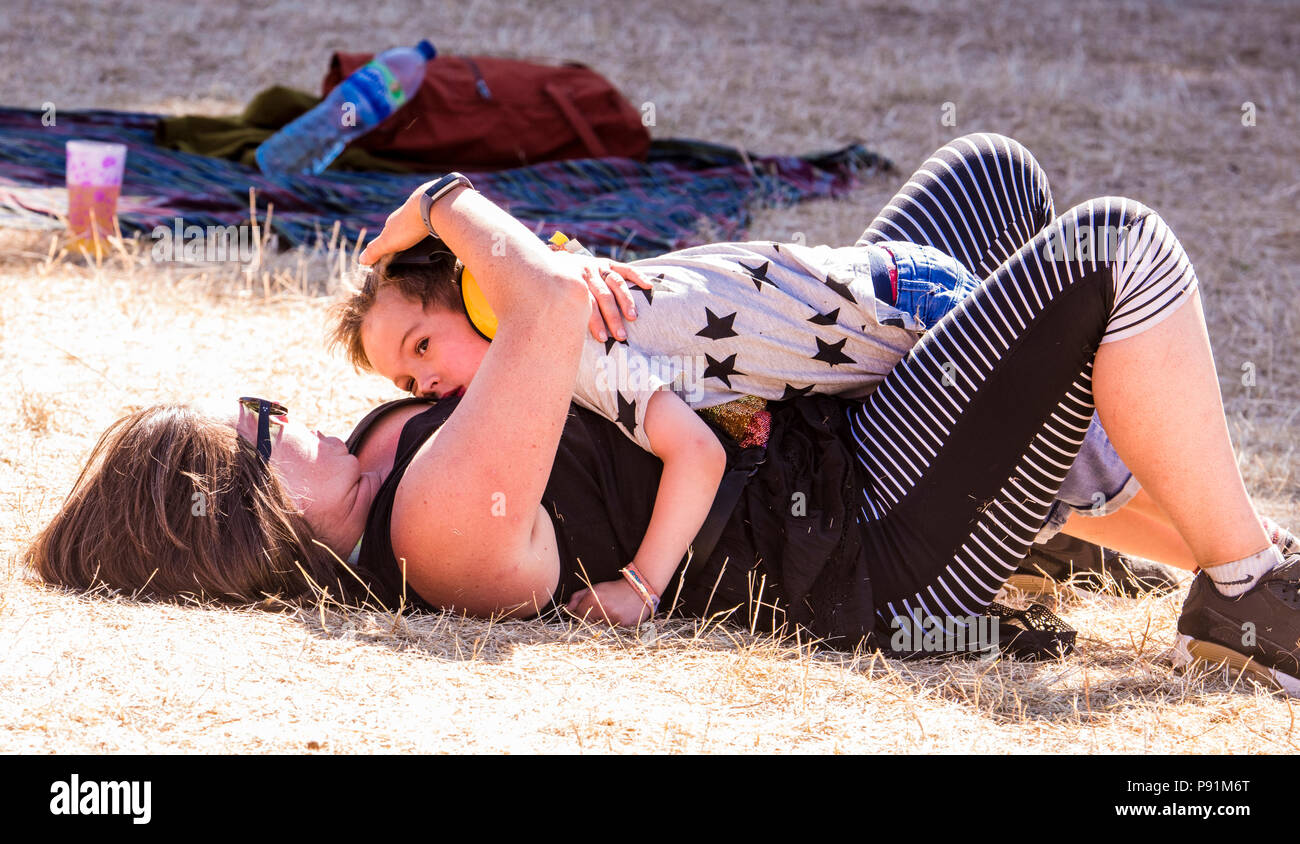 Mother and son cuddling on grass, at Latitude Festival, Henham Park, Suffolk, England, 14th July 2018 Stock Photo