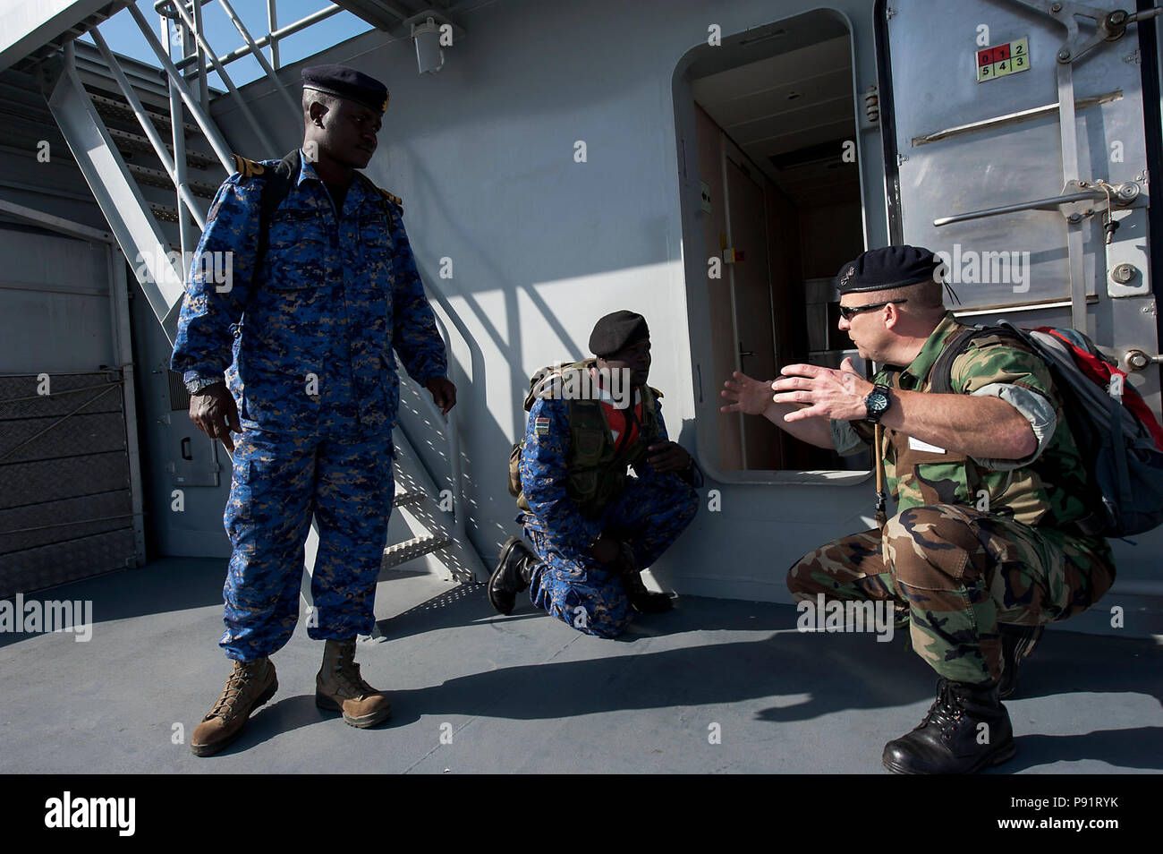 A Dutch maritime interdiction operations evaluator, right, works with two members of the Gambian boarding team aboard the Moroccan navy offshore patrol vessel RMN Bir Anzarane (341) during Saharan Express 2013. Stock Photo