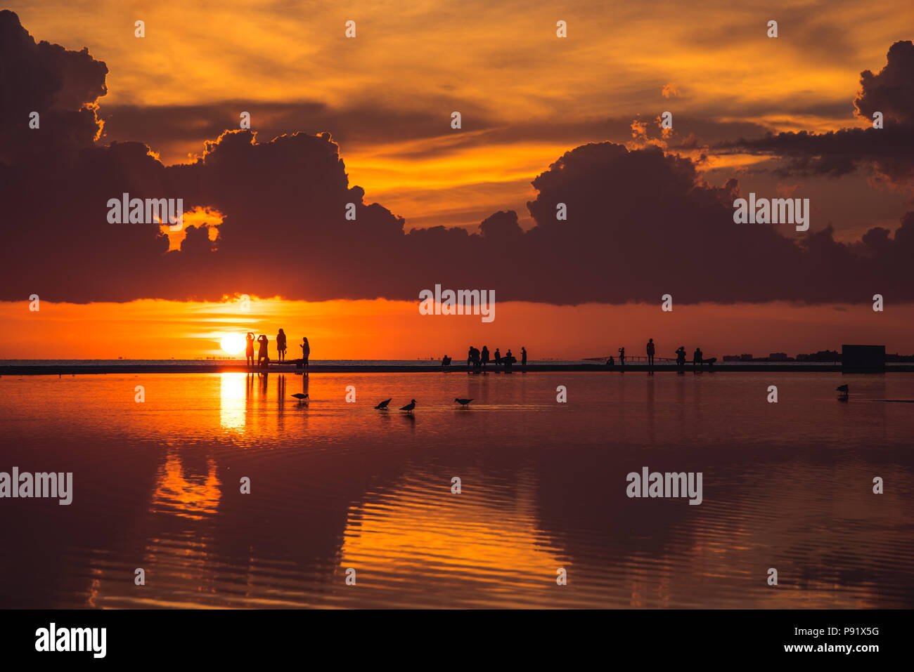 Fort Myers Beach during a sunset. the sky is reflected on a large puddle that accumalates on the beach sand after it rains. Stock Photo