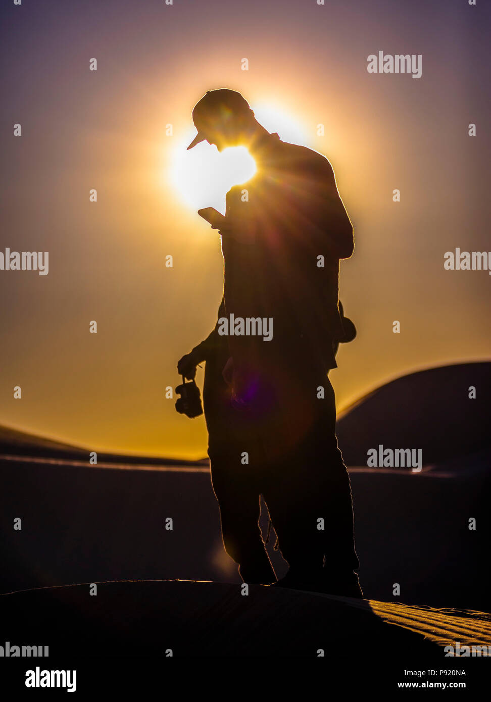 Man using phone in sand dunes Stock Photo
