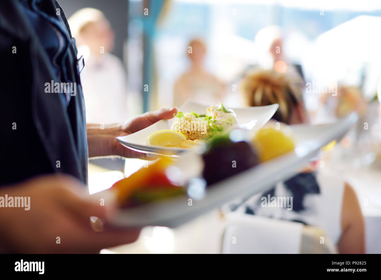 Waiter carrying plates with meat dish on some festive event, party or