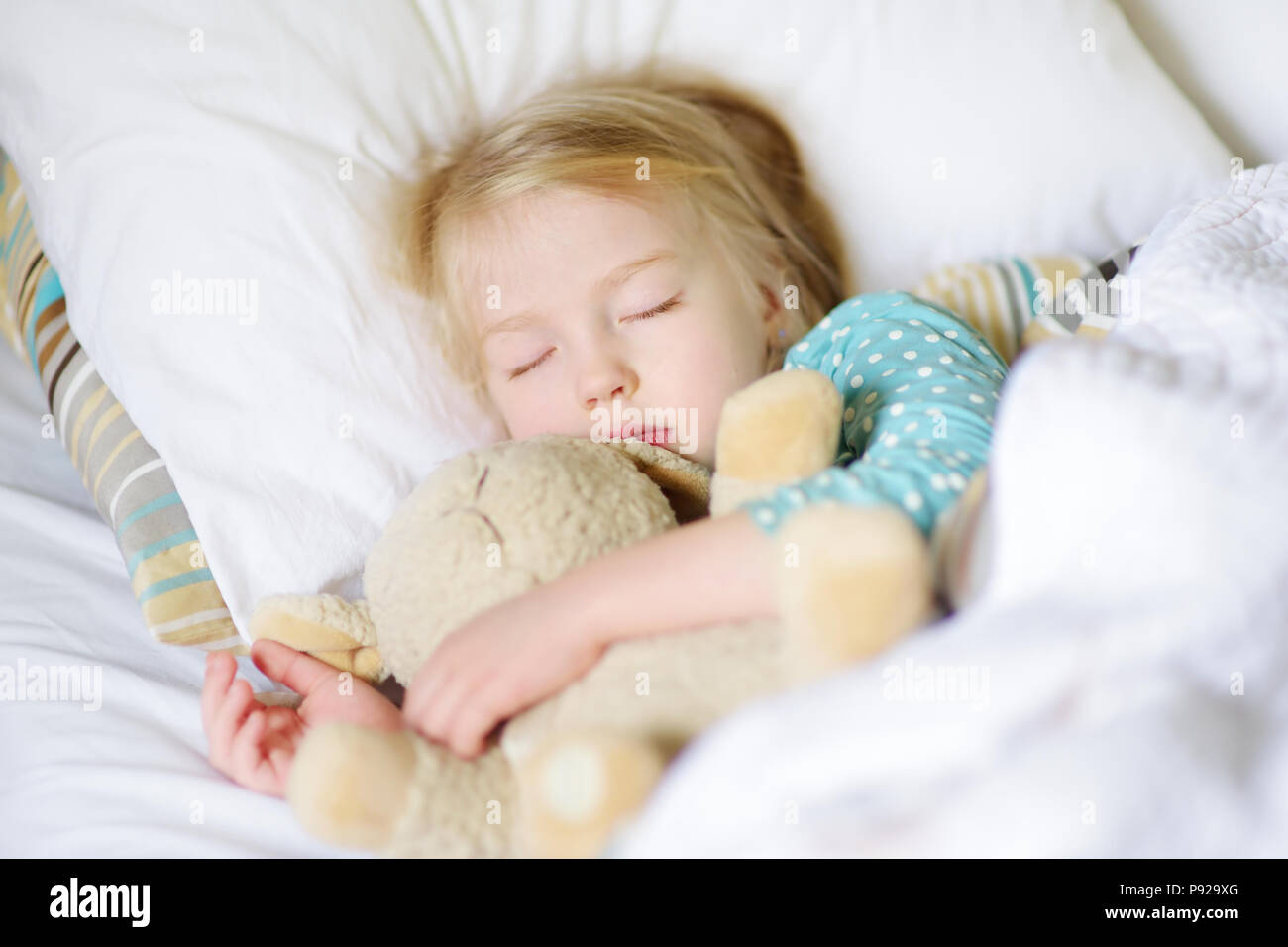Adorable little girl sleeping in the bed with her toy. Tired child