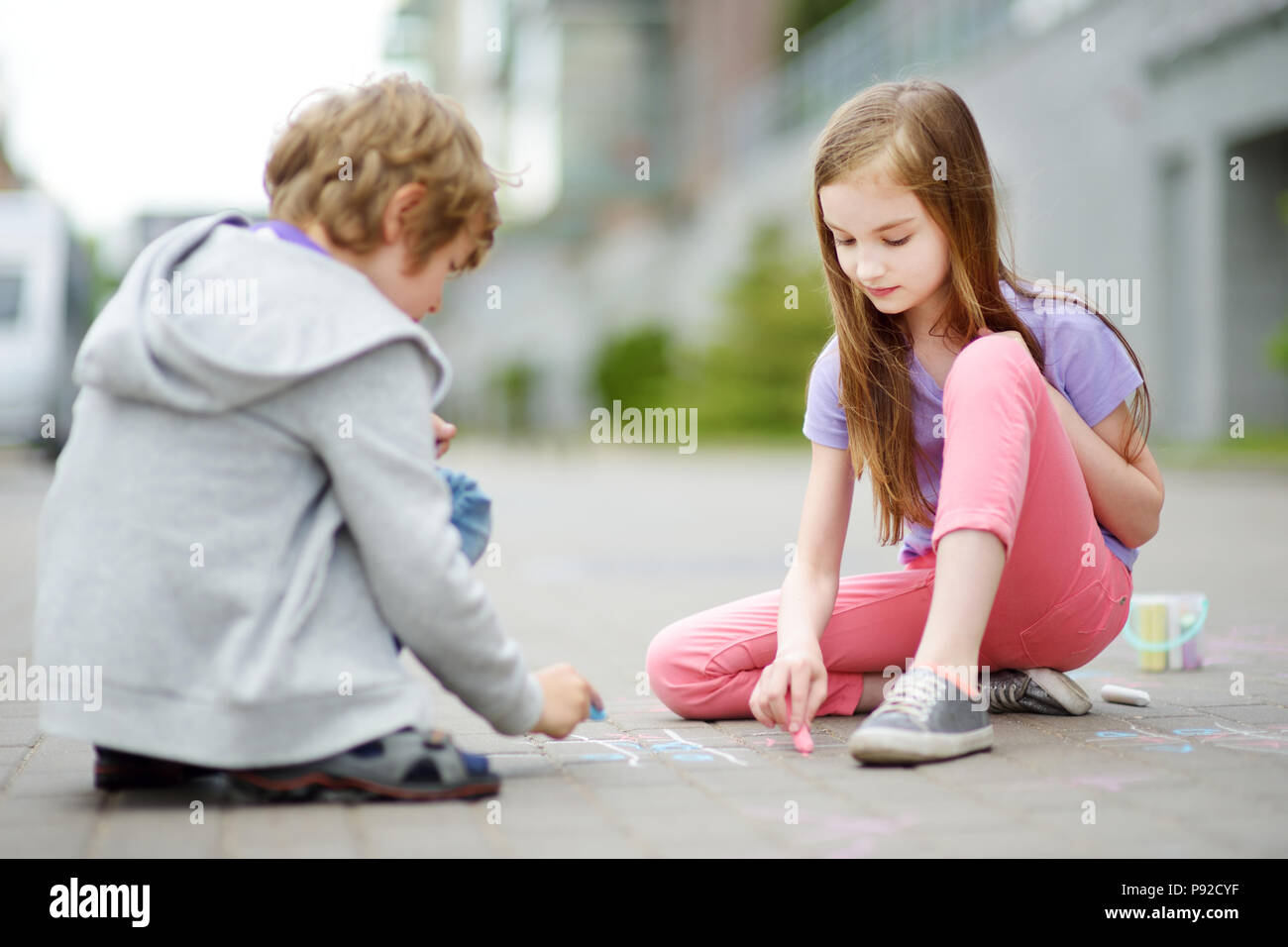 Two happy children drawing with colorful chalks on a sidewalk. Summer ...