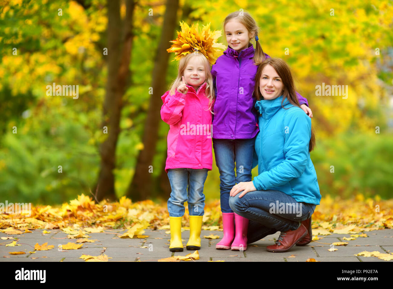 Two cute little girls and their mother having fun on beautiful autumn ...