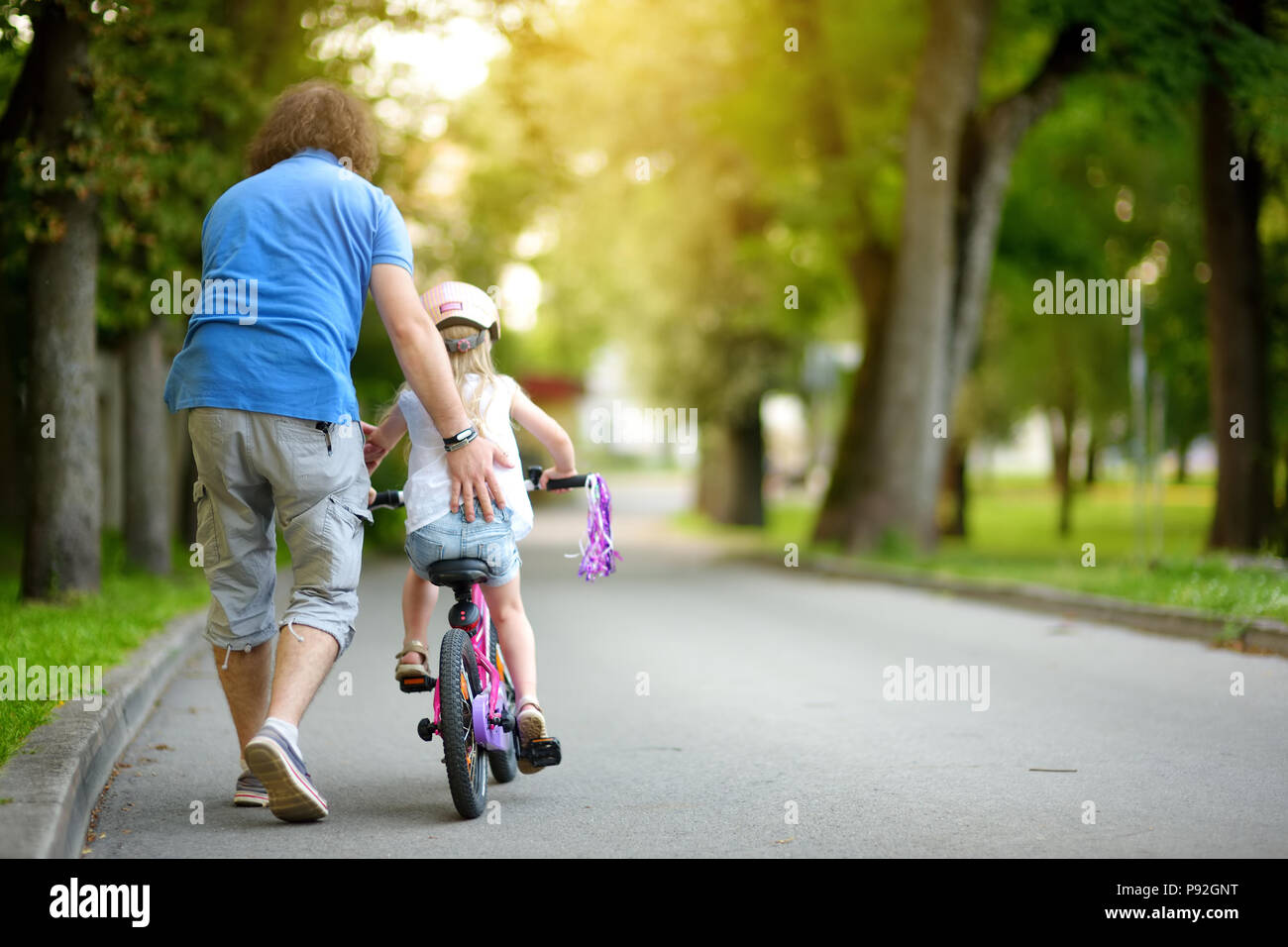 Happy father teaching his little daughter to ride a bicycle. Child