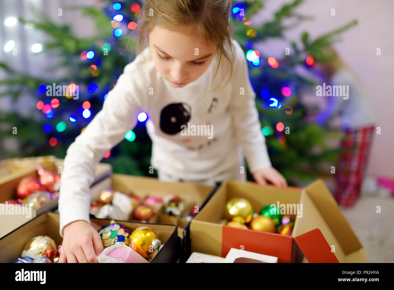 Adorable little girl decorating the Christmas tree with colorful glass ...