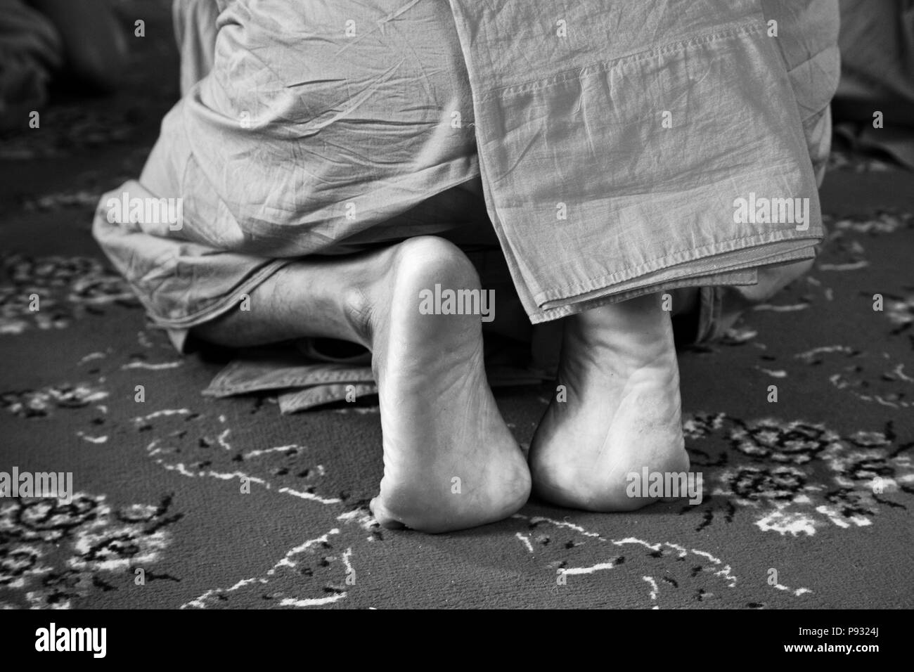 Feet of a PROSTRATING THAI HINAYANA MONK at the Buddhist Temple of WAT INTHARAVIHAN or INDRAWIHAN - BANGKOK, THAILAND Stock Photo