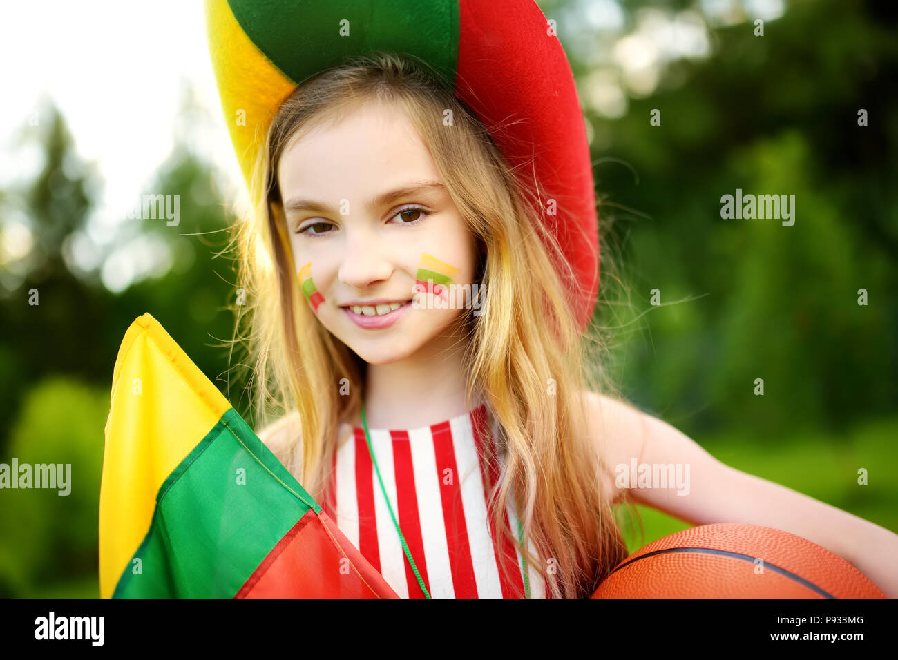 Funny little girl supporting and cheering her national basketball team during basketball championship. Cute Lithuanian team fan. Stock Photo