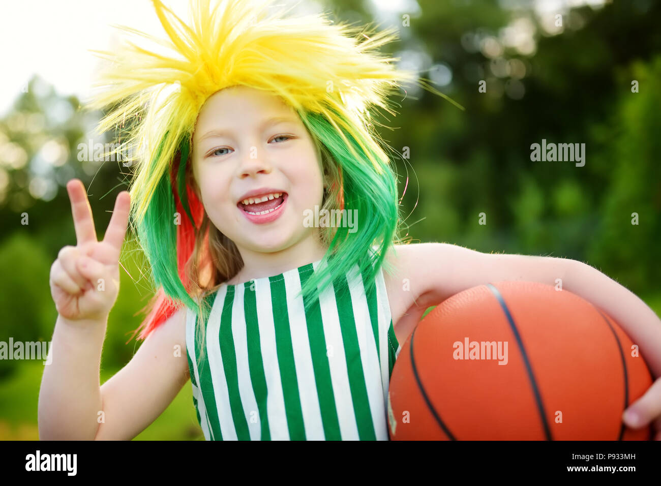 Funny little girl supporting and cheering her national basketball team during basketball championship. Cute Lithuanian team fan. Stock Photo